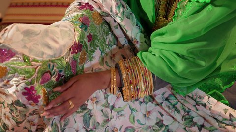 تجهيز وتنسيق الهدايا ليوم الزفاف، العادات والتقاليد الإماراتية في مراسم الزواج, تصوير مقرب ليد امراة عربيه خليجيه اماراتية تقوم بتحضير الجلابيات الاماراتية للعروس، الزي الشعبي التراثي التقليدي