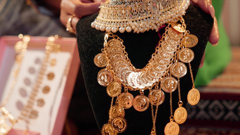 ذهب محلي اماراتي وطني، العادات والتقاليد الإماراتية في مراسم الزواج، تقديم الهدايا في المناسبات السعيدة، تصوير مقرب ليد امراة عربيه خليجيه اماراتية تحمل بيديها عقد من الذهب لتقديمه للعروس