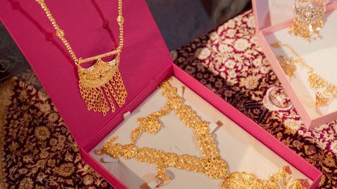 العادات والتقاليد الإماراتية في مراسم الزواج، تقديم الهدايا في المناسبات السعيدة، تصوير مقرب ليد امراة عربيه خليجيه اماراتية تحمل بيديها عقد من الذهب لتقديمه للعروس، ذهب محلي اماراتي وطني