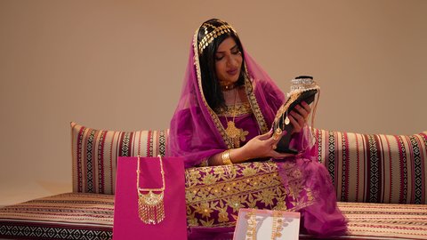ايماءات السعاده و السرور، عادات وتقاليد الزواج في الامارات، تقديم الهدايا في المناسبات السعيدة، عروس عربيه خليجيه اماراتية تحمل بيديها عقد من الذهب ، التزين بالحلي الذهبية الفاخرة، ذهب محلي اماراتي وطني