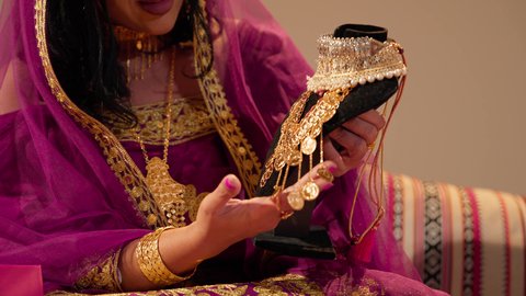 عادات وتقاليد الزواج في الامارات، تقديم الهدايا في المناسبات السعيدة، تصوير مقرب لعروس عربيه خليجيه اماراتية تحمل بيديها عقد من الذهب ، التزين بالحلي الذهبية الفاخرة، ذهب محلي اماراتي وطني