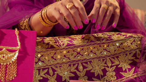 اختيار مجوهرات ذهبية فاخرة، ذهب محلي اماراتي وطني، العادات الإماراتية في تجهيز العروس، تصوير مقرب ليد عروس عربية خليجيه اماراتية تقوم بارتداء الخاتم الذهبي فى اصبعها