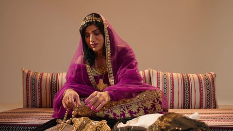 Emirati traditions in weddings, increasing bonds of love through gifting and appreciation, an Arab Gulf Emirati bride wearing a colorful abaya holding in her hands a traditional masterpiece made of gold, gestures of happiness and joy, local Emirati gold.