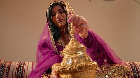 تعابير السعادة و السرور، مفهوم الإهداء والتقدير، عادات وتقاليد الأعراس الإماراتية، تصوير مقرب لعروس عربية خليجية إماراتية ترتدي العباءة الملونه تمسك بيديها تحفة تقليدية من الذهب ، ذهب محلي وطني اماراتي