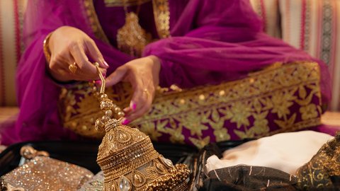 مفهوم الإهداء والتقدير، عادات وتقاليد الأعراس الإماراتية، تصوير مقرب لعروس عربية خليجية إماراتية ترتدي العباءة الملونه تمسك بيديها تحفة تقليدية من الذهب ، ذهب محلي اماراتي وطني