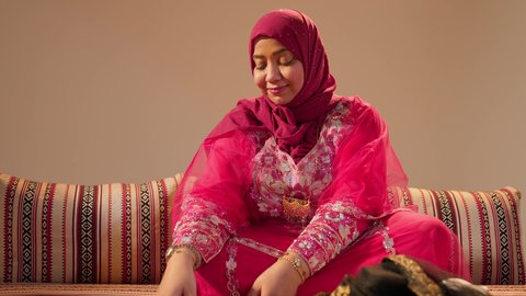 ايماءات السعادة و السرور، تحضيرات ما قبل تقديم الهدايا للعروس، مراسم الاعراس و المناسبات في الامارات ، العطاء والاحتفال بالمناسبات السعيدة،  ام العريس ترتدي عباءة مطرزة تمسك حقيبة ثمينه