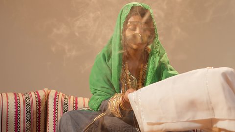 العادات الإماراتية في تجهيز الهدايا للعروس، مراسم الاعراس و المناسبات في الامارات ، العطاء والاحتفال بالمناسبات السعيدة، امراة عربية خليجية إماراتية ترتدي عباءة مطرزة تمسك بقطعه قماش مطرز