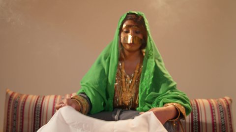 تجهيزات الزفاف الإماراتي، مراسم الاعراس و المناسبات في الامارات ، العطاء والاحتفال بالمناسبات السعيدة، امراة عربية خليجية إماراتية ترتدي عباءة مطرزة تمسك بقطعه قماش مطرز