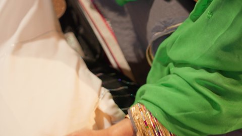 مراسم الاعراس و المناسبات في الامارات ، العطاء والاحتفال بالمناسبات السعيدة، الاستعداد لتقديم الهدايا للعروس، تصوير مقرب ليد امراة عربية خليجية إماراتية ترتدي عباءة مطرزة تمسك بقطعه قماش مطرز