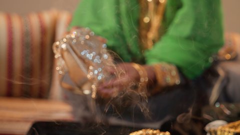 مراسم الزواج في المجتمع الإماراتي، تصوير مقرب ليد امراة عربية خليجية إماراتية ترتدي عباءة مطرزة تحمل حقيبة من الذهب لتقديمها للعروس في يوم الزفاف،  العطاء والاحتفال بالمناسبات السعيدة