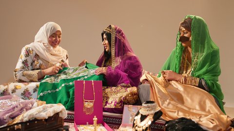 تقاليد الزواج في المجتمع الإماراتي، امراة عربيه خليجيه اماراتية برفقة ام العريس  يهدون العروس جلابية مطرزة فاخرة بمناسبة حفل زفافها، ايماءات السعادة و السرور