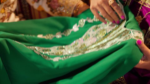 The Emirati customs and traditions in preparing the bride, a close-up shot of the groom's mother gifting the bride an exquisite embroidered dress on the occasion of her wedding, manifestations of joy and celebration during happy occasions.