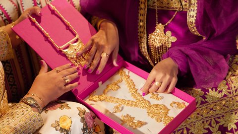 مظاهر الفرح والاحتفال بالمناسبات السعيدة، تصوير مقرب ليد أم العريس تقدم للعروس علبة فاخرة تحتوي على إكسسوارات ذهبية ضمن طقوس الزواج الإماراتي، العادات والتقاليد الخليجية الاماراتية الأصيلة، ذهب محلي اماراتي وطني