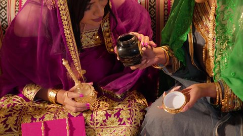 العادات الشعبية في الأعراس الخليجية الاماراتية، تصوير مقرب لامراة عربيه خليجيه اماراتية ترتدي العباءة المطرزة  تمسك بعلبة بن تقدمها للعروس لتشم رائحتها، تحضيرات العروس قبل الزفاف