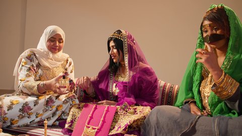 Preparations for the traditional Emirati wedding, inherited customs that reflect the heritage and local culture in joyful occasions, authentic Emirati wedding traditions, the groom's mother wears an embroidered abaya and perfumes the bride, gestures of happiness and joy.
