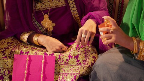 تقاليد الأعراس الإماراتية الأصيلة، عادات متوارثة تعكس التراث والثقافة المحلية في المناسبات السعيدة، تصوير مقرب ليد امراة عربيه خليجيه اماراتية ترتدي الزي التقليدي المطرز تقوم بتعطير العروس