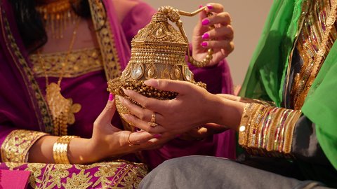 تقاليد الزواج في المجتمع الإماراتي، تصوير مقرب ليد أم العريس ترتدي الزي المطرز تقوم باعطاء تحفة تقليدية من الذهب للعروس في يوم زفافها ، مظاهر الكرم والاحتفال بالزفاف