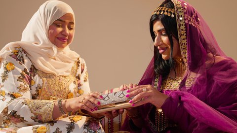 ايماءات السعادة و السرور ، ام العريس ترتدي الزي التقليدي المطرز تقوم باهداء العروس حقيبة ثمينه فى يوم زفافها، مظاهر الود والمحبة في المناسبات الاجتماعية، العادات و الطقوس الاماراتية فى الزواج