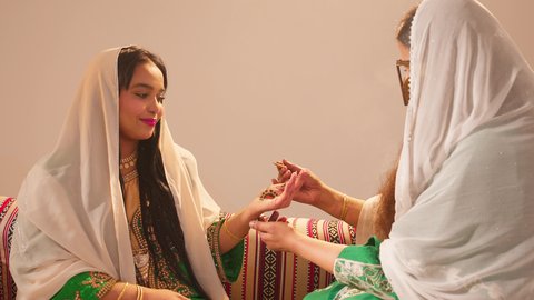 أزياء تقليدية شعبية نسائية، فنون ونقوش وزخارف يدويه من مواد طبيعيه، التجمل والتزيين والاهتمام بالمظهر الخارجي، عادات وتقاليد في المناسبات والأفراح السعيدة، إمرأة عربية خليجية إماراتية تقوم بالرسم والنقش على يد شابة سعودية باستخدام الحناء الحمراء