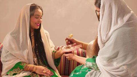 تعابير السعادة والسرور، أزياء تقليدية شعبية نسائية، فنون ونقوش وزخارف يدويه من مواد طبيعيه، التجمل والتزيين في يوم الزفاف، عادات وتقاليد في المناسبات والأفراح السعيدة، إمرأة عربية خليجية إماراتية تقوم بالرسم والنقش على يد شابة سعودية باستخدام الحناء الحمراء