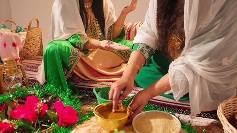 أزياء تقليدية شعبية نسائية، فنون ونقوش وزخارف يدويه من مواد طبيعيه، التجمل والتزيين والاهتمام بالمظهر الخارجي، عادات وتقاليد في المناسبات والأفراح السعيدة، إمرأة عربية خليجية إماراتية تقوم بالرسم والنقش على يد شابة سعودية باستخدام الحناء الحمراء