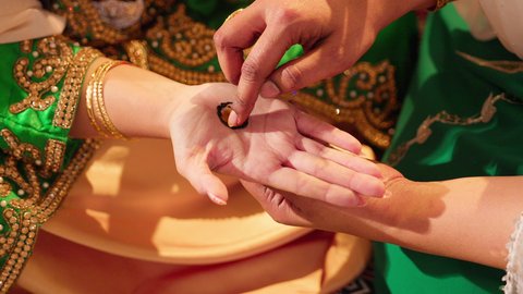 التجمل والاهتمام بالمظهر الخارجي على الطريقة الشعبية، زخارف وفنون يدويه من مواد طبيعيه، عادات وتقاليد في المناسبات والأفراح السعيدة، تصوير مقرب ليد إمرأة عربية خليجية إماراتية ترتدي الزي التراثي و تقوم برسم و نقش الحنة على يد شابة، مهن وأزياء تقليدية شعبية نسائية