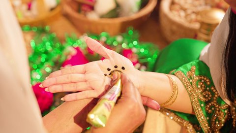 التجمل والاهتمام بالمظهر الخارجي على الطريقة الشعبية، زخارف وفنون يدويه من مواد طبيعيه، عادات وتقاليد في المناسبات والأفراح السعيدة، تصوير مقرب ليد إمرأة عربية خليجية إماراتية ترتدي الزي التراثي و تقوم برسم و نقش الحنة على يد شابة، مهن وأزياء تقليدية شعبية نسائية