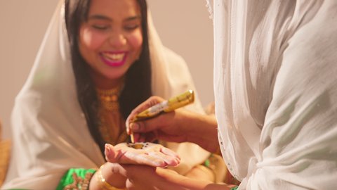 ايماءات السعادة والسرور، أزياء تقليدية شعبية نسائية، فنون ونقوش وزخارف يدويه من مواد طبيعيه، التجمل والتزيين في يوم الزفاف، عادات وتقاليد في المناسبات والأفراح السعيدة، إمرأة عربية خليجية إماراتية تقوم بالرسم والنقش على يد شابة سعودية باستخدام الحناء الحمراء