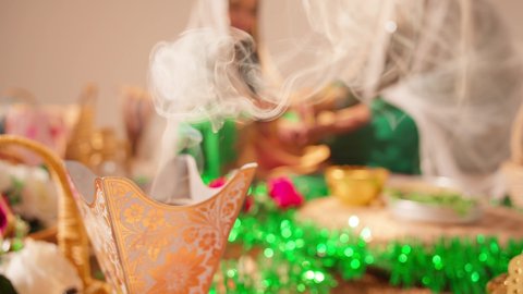 التطيب بالمسك والعود، مراسم الأعراس والزواج، أصالة العادات والتقاليد الخليجية، الاحتفال بالمناسبات والأفراح السعيدة, عروس عربية خليجية اماراتية مبتسمة ترتدي الزي الشعبي، تصوير مقرب لحامل البخور( المبخرة )
