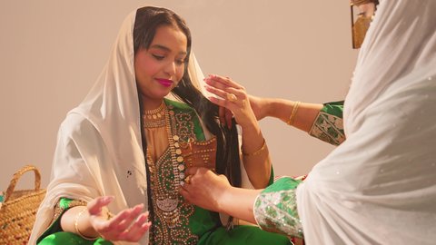 مراسم الأعراس والزواج، أصالة العادات والتقاليد الخليجية، الاحتفال بالمناسبات والأفراح السعيدة, عروس عربية خليجية اماراتية مبتسمة ترتدي الزي الشعبي تحمل بيدها حامل البخور( المبخرة ) تقوم بتبخير نفسها، التطيب بالمسك والعود