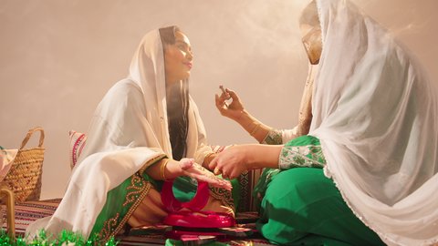 ايماءات السعادة والفرح، الاحتفال بليلة العمر، منتجات ومساحيق التجميل, مناسبات وأفراح واحتفالات سعيدة، العناية والاهتمام بالأناقة والجمال، مفهوم التزين والاطلالة المتألقة، سيدة عربية خليجية اماراتية تقوم بوضع أحمر الشفاه للعروسة