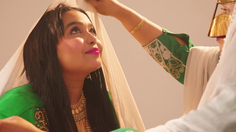 الاهتمام بالأناقة والمظهر الخارجي، مفهوم التزين والاطلالة المتألقة، سيدة عربية خليجية اماراتية ترتدي الزي التقليدي والبرقع تقوم بوضع الطرحة للعروسة، إيماءات السعادة والفرح ، الاحتفال بليلة العمر، مناسبات وأفراح واحتفالات سعيدة