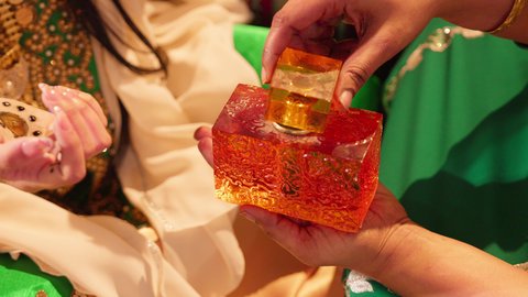 مفهوم الأناقة والاهتمام بالمظهر الخارجي، عطور ذات روائح فاخرة وفريدة، تصوير مقرب لسيدة عربية اماراتية خليجية تحمل زجاجة عطرية تقوم بوضع العطر لعروس ترتدي الزي التراثي، مراسم الأعراس والاحتفالات في الامارات، الفرح و السرورفي يوم الزواج