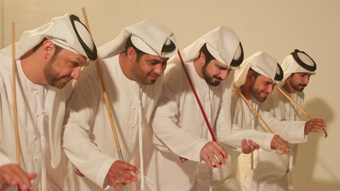 Al Ayala is a traditional dance in a festive atmosphere, celebrating the national holiday with the dance of the khayrzan. It features folk dances during national events and festivals. A close-up shot of a group of Arab Gulf Emirati men wearing traditional attire dancing a folk dance, showcasing heritage folklore performances.
