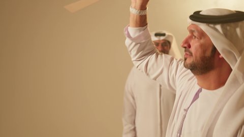 Teachings of folk dance, the popular Emirati dance Al Ayala, harmony and coordination in dance movements during a national holiday, a traditional celebration and national occasion, the heritage folklore troupe, celebrating the national day, a close-up shot of a group of Arab Gulf Emirati men wearing traditional attire dancing.