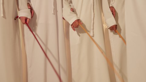 العيالة رقصة شعبيه في المهرجانات والمناسبات، التفاعل والرقص بالخيرزان، ايماءات السرور والفخر، احتفال تقليدي ومناسبة وطنية، فرقة الفلكلور التراثي، الاحتفال بالعيد الوطني، تصوير مقرب لمجموعة من الرجال عربيين خليجيين اماراتيين يرتدون الزي التقليدي يرقصون