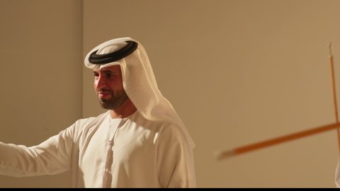 Dancing on a national holiday, Al Ayala is a folk dance at festivals, interaction and dancing with sticks, a traditional celebration and a national occasion, a heritage folklore troupe, celebrating the national holiday, a close-up shot of an Emirati Gulf Arab man wearing traditional attire dancing with a group.
