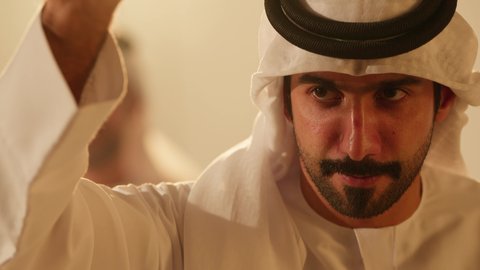 الرقصة والعرضة الاماراتية الشعبية العيالة, التناغم والرقص بالخيرزان، تناسق وتناغم في حركات الرقص في عيد وطني، احتفال تقليدي ومناسبة وطنية، فرقة الفلكلور التراثي، الاحتفال بالعيد الوطني، تصوير مقرب لرجل عربي خليجي اماراتي يرتدي الزي التقليدي يرقص مع فرقة