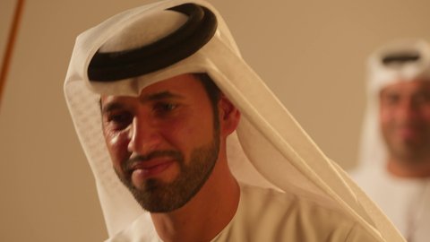 Harmony and dancing with the khayrzan, coordination and harmony in the dance movements during a national holiday, Al Ayala is a folk dance at festivals, a traditional celebration and a national occasion, the heritage folklore troupe, celebrating the national holiday, a close-up shot of an Emirati Gulf Arab man wearing traditional attire dancing with a team.