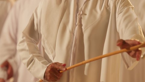 Heritage arts and performances, celebrating the national holiday with the traditional dance using the cane is part of the traditional attire of the UAE, folk dances during national occasions, festivals, and holidays, a close-up shot of a man performing the traditional Yawla dance, wearing traditional attire at a national event, a folklore performance troupe.