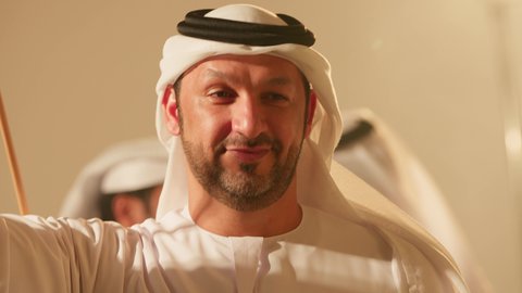 تعابير السرور والفخرفي عروض الفلكلور التراثي، الاحتفال بالعيد الوطني بالرقص بالخيرزان جزء من الزي التقليدي للامارات، رقصات شعبيه في المناسبات الوطنية والأعياد، تصوير مقرب لمجموعة من الشباب العربين الخليجين الاماراتيين  يرقصون رقصة شعبية اليولة