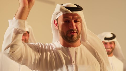 خلفية فرقة عروض فليكلوز تراثي، الاحتفال بالعيد الوطني بالرقص بالخيرزان جزء من الزي التقليدي ، رقصات شعبيه في المناسبات الوطنية والمهرجان، تصوير مقرب لرجلعربي خليجي اماراتي يرقص رقصة شعبية اليولة، ارتداء زي التقليدي في مناسبة وطنية