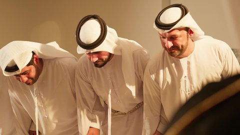 The Al-Ayala and folk arts, traditional arts and performances, celebrating the national holiday with movements and details that are part of the traditional attire of the UAE, folk dances during national occasions and holidays, a close-up shot of a group of Emirati Gulf Arab youth dancing the traditional Yawla dance.