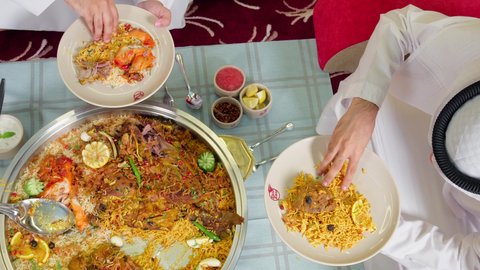 وصفات الأكلات الشعبية ، سفرة مليئة بأصناف المأكولات والمقبلات الشهية، الوجبات والأطباق الرئيسية على مائدة الطعام، مطاعم ومطابخ الامارات العربية، أنواع الأطعمة الشرقية على الموائد, تصوير مقرب لرجل عربي خليجي اماراتي يرتدي الكندورة و الغتره يقوم بتناول الطعام فى المطعم