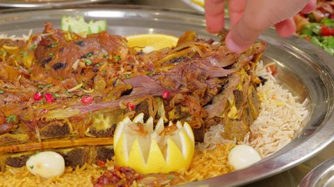 Restaurants for Eastern Arab cuisine, popular Gulf Emirati Arab dishes, delicious meals, close-up shot of the hand of an Emirati Gulf Arab man eating fresh meat in the restaurant.