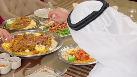 أكلات شعبية عربية خليجية اماراتية، مطاعم للمأكولات العربية الشرقية، وجبات الطعام الشهية، تصوير مقرب من الخلف لرجل عربي خليجي اماراتي يرتدي الكندورة و الغتره يقوم بتناول الطعام فى المطعم