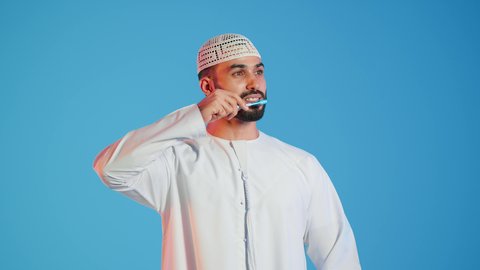 روتين نظافة الفم اليومية ،بورتريه لرجل عربي خليجي اماراتي  يقوم بتنظيف الأسنان بفرشاة الأسنان ، مفهوم العناية والإهتمام بصحة ونظافة الأسنان ، تجنب تسوس الاسنان وامراض اللثة ، خلفية ملونة