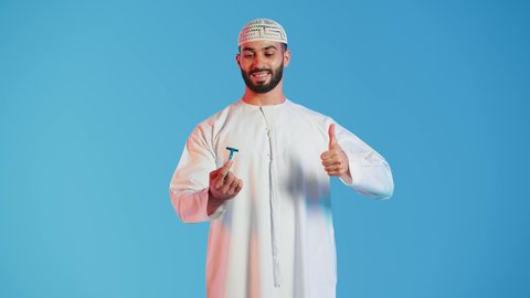 شفرة حلاقة رجالية، بورتريه  لرجل عربي خليجي اماراتي يرتدي الزي الاماراتي  يمسك بيده شفرة الحلاقة بايماءات الموافقه والرضا ، مفهوم العناية بالبشرة والنظافة ، الإهتمام المظهر الخارجي ،  خلفية ملونة