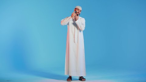 الإهتمام المظهر الخارجي ، مفهوم العناية بالبشرة والنظافة ،بورتريه مقرب لرجل عربي خليجي اماراتي يرتدي الزي الاماراتي، يقوم بإزالة شعر الوجه بإستخدام شفرة الحلاقة ، شفرة حلاقة رجالية، خلفية ملونة