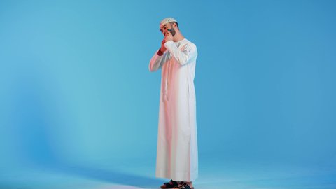 بورتريه  مقرب لرجل عربي خليجي اماراتي يرتدي الزي الاماراتي، يقوم بإزالة شعر الوجه بإستخدام شفرة الحلاقة ، مفهوم العناية بالبشرة والنظافة ، الإهتمام المظهر الخارجي ، شفرة حلاقة رجالية، خلفية ملونة